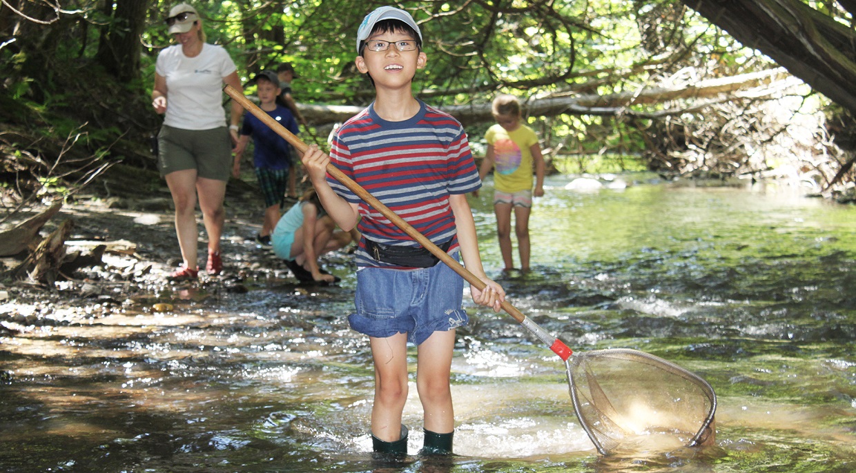 a young boy explores at stream at Claremont Field Centre nature day camps