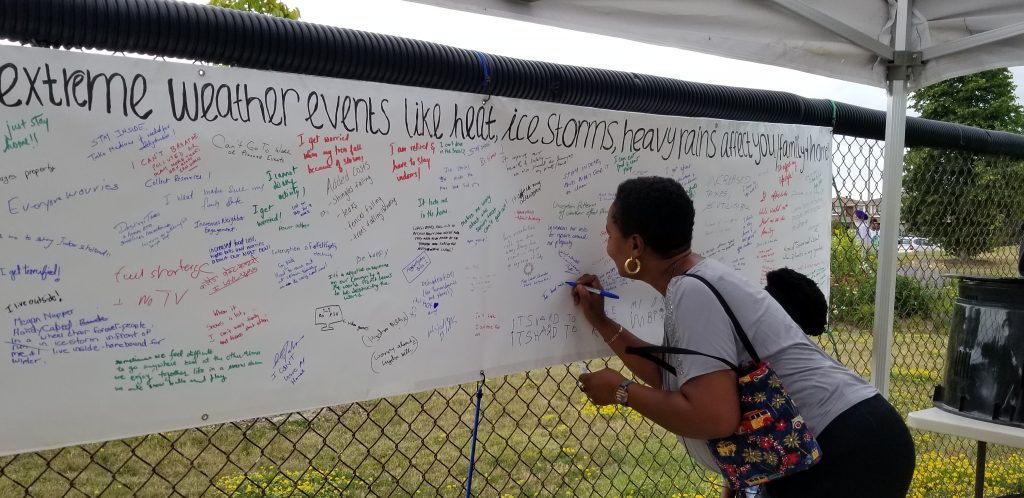 woman writing her experience with extreme weather on a white banner filled with other peoples comments