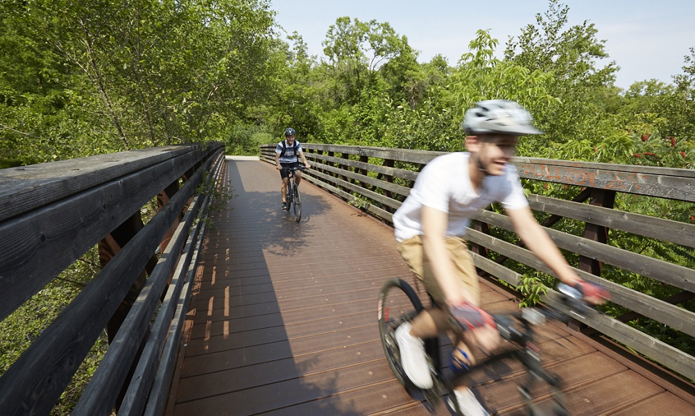 Two youth riding their bikes on a pedestrian bridge