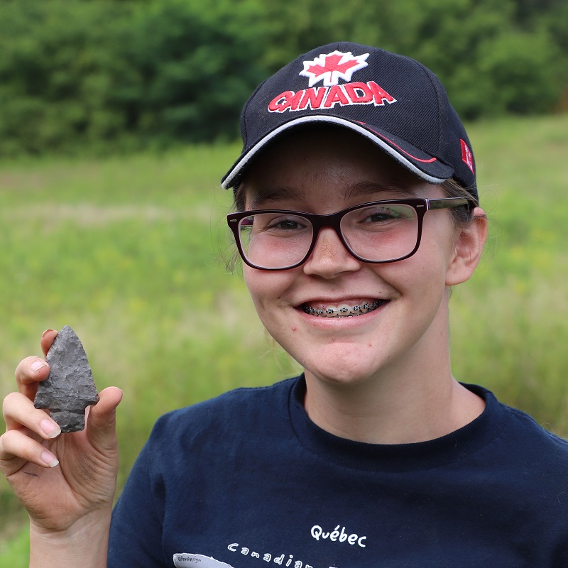 Boyd Archaeological Field School student displays artifact at dig site