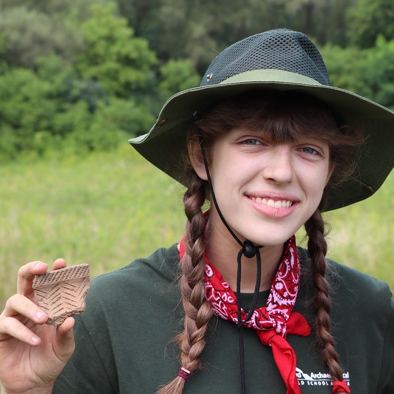 Boyd Archaeological Field School student displays artifact at dig site