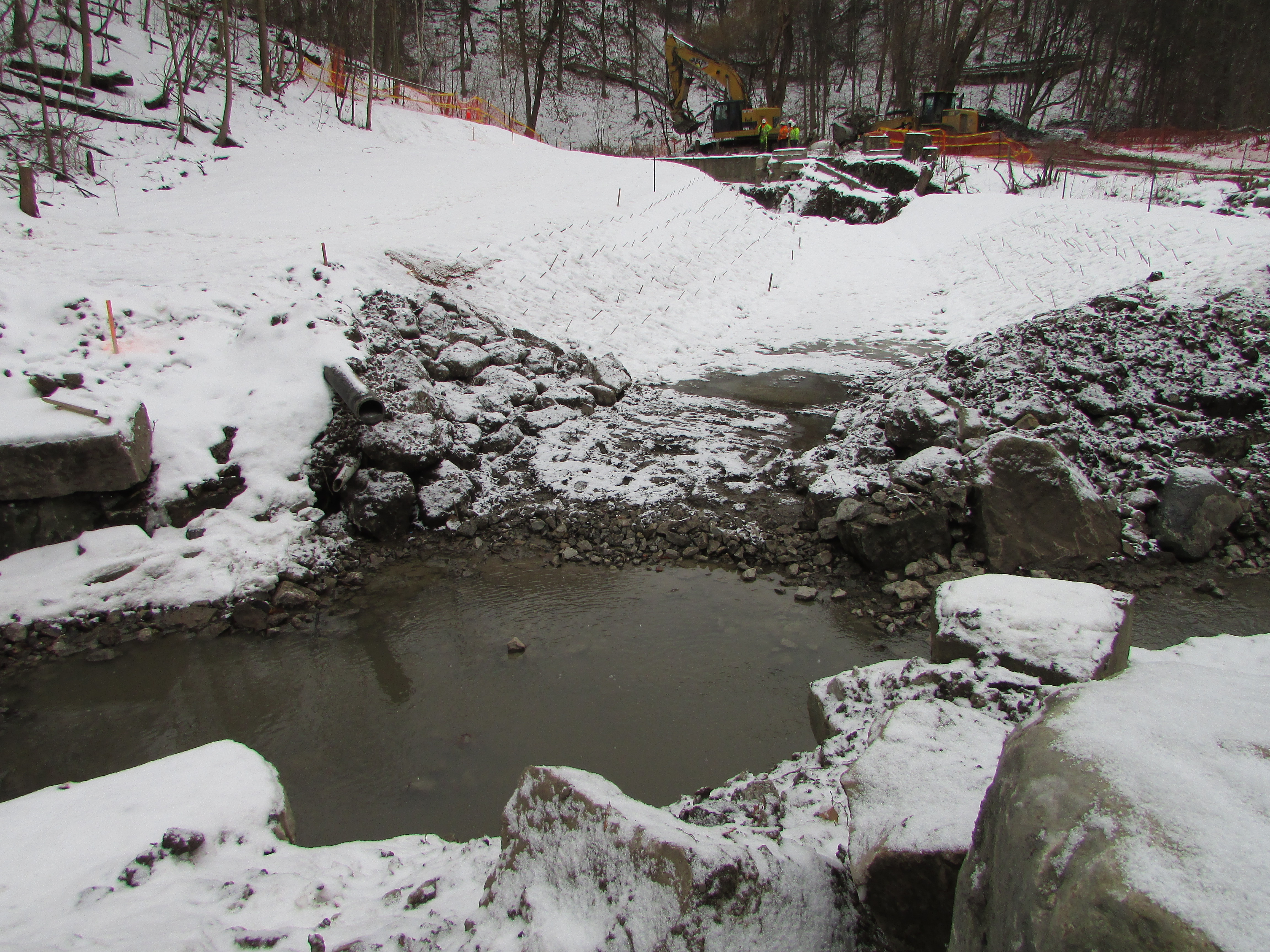 TRCA construction staff can be seen in the distance working with the excavator to prepare the upstream section of Yellow Creek for the dismantling of the stone and mortar retaining wall. Source: TRCA, 2019.