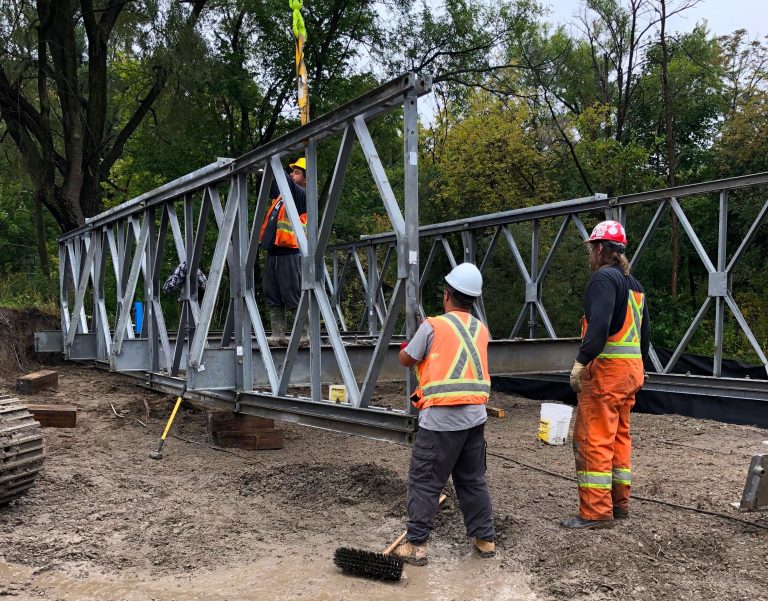 construction crew installs temporary bridge