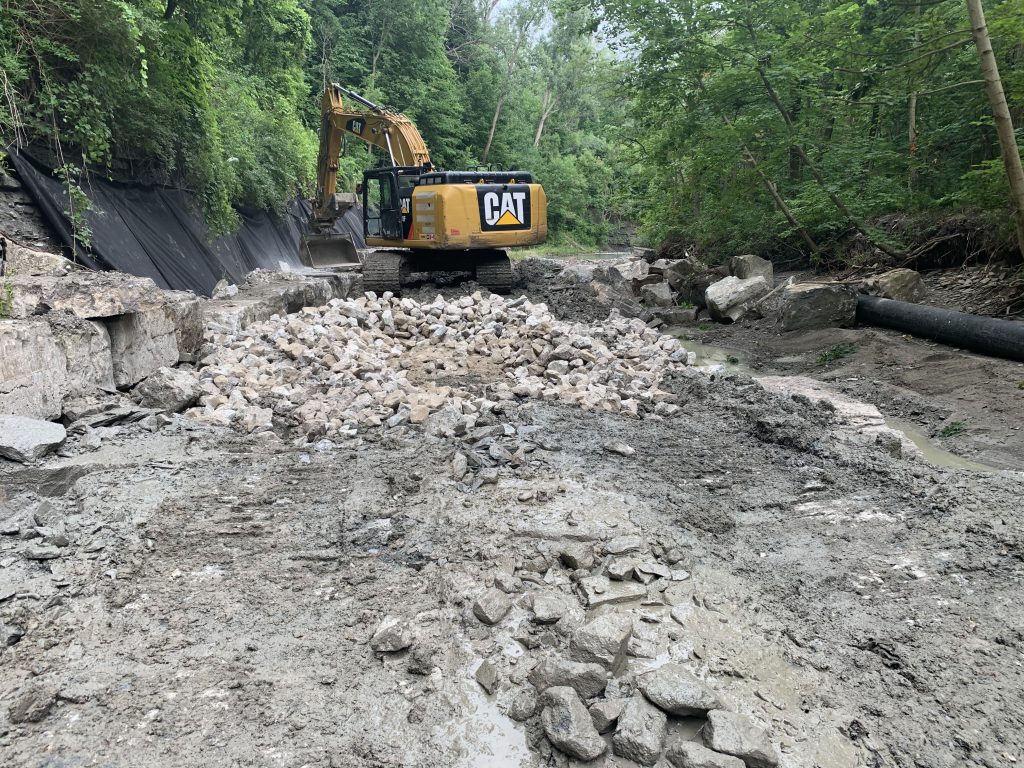 An excavator working on construction of an armourstone wall along Mimico Creek